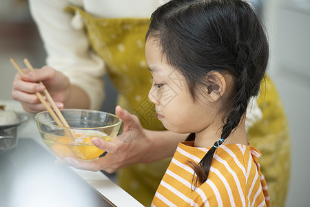 厨房里帮助妈妈制作料理的小女孩图片