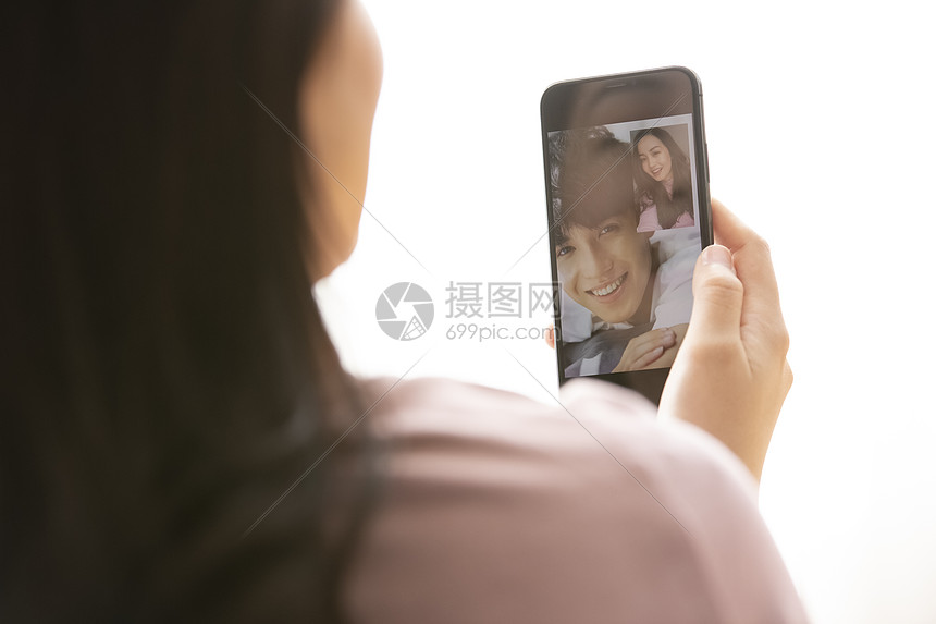 年轻女子拿着手机与恋人视频通话图片