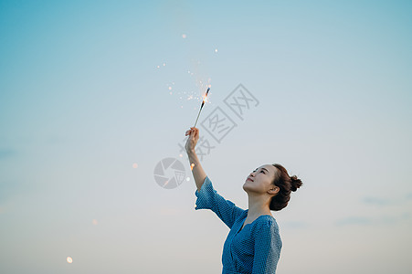 海边放烟花的年轻女子图片