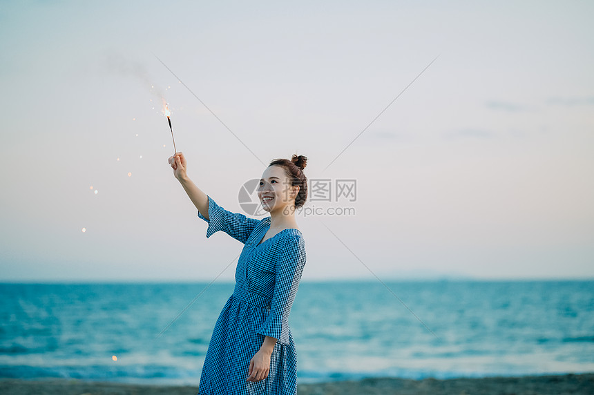 海边放烟花的年轻女子图片