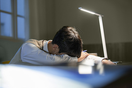 高中男学生夜晚趴在课桌上睡觉图片