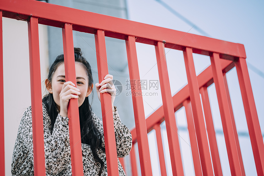 蹲在栏杆旁的年轻女子图片