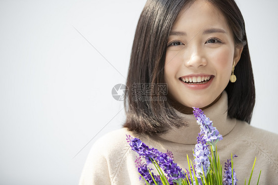 太阳光快乐中日手捧花的年轻女子的画像图片