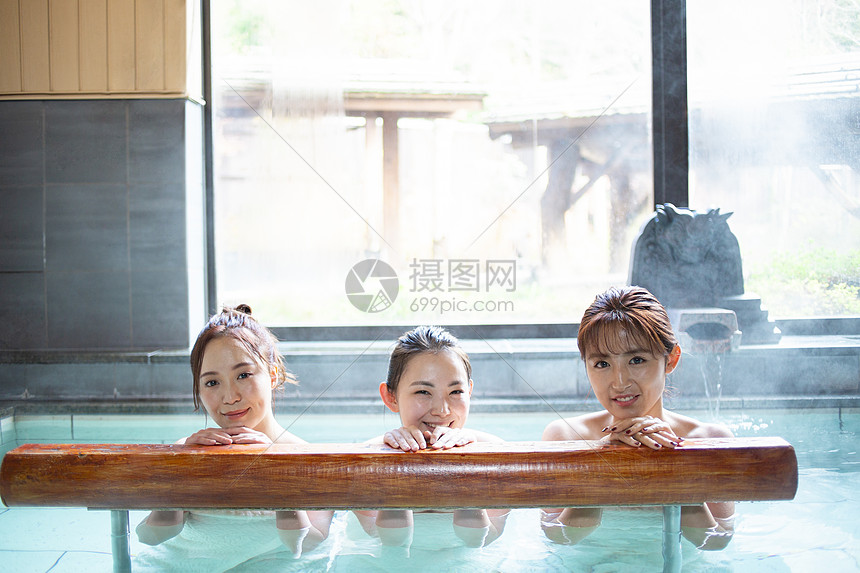 人物寄宿年轻妇女和朋友享受露天浴池图片