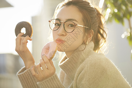 青年女子双手拿着甜甜圈图片