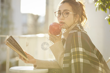 吃苹果看书的青年女子图片