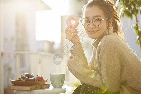 拿着甜甜圈微笑的年轻女子图片