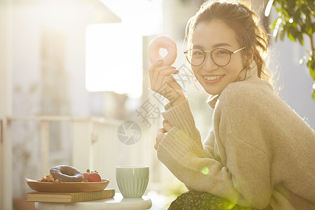 拿着甜甜圈微笑的青年女子图片