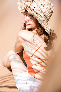 旅行日光防晒油泳装的一名妇女坐在海滩图片