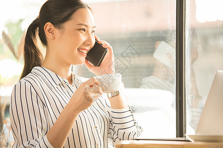 拿着咖啡接听电话的商务女性图片