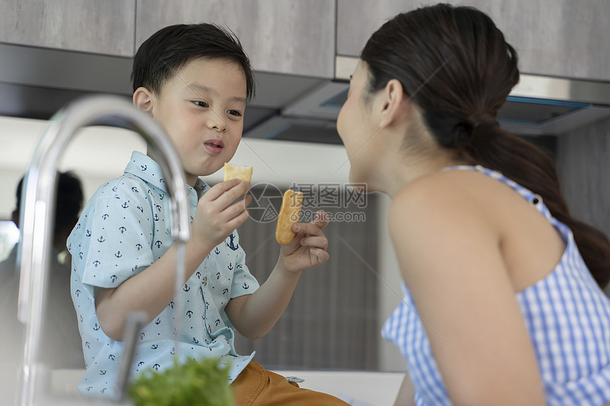 母亲和男孩在厨房里吃东西图片