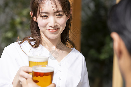喝啤酒干杯的年轻女子图片