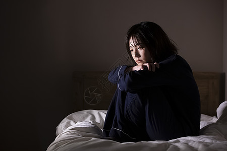 坐在床上孤独压抑的年轻女子背景图片