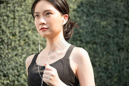 户外跑步戴着耳机的年轻女子图片
