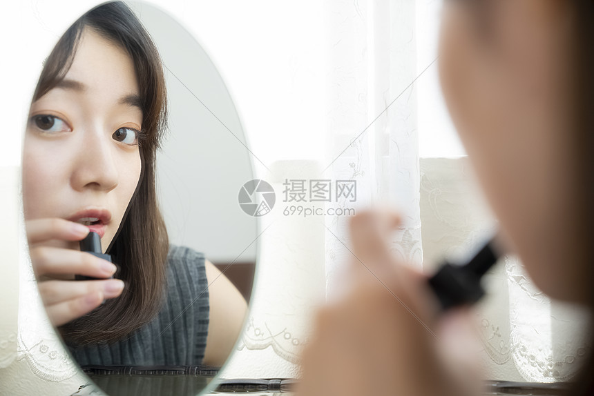 照镜子涂口红的年轻女子图片