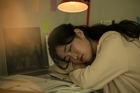 趴在书桌上沉睡的女大学生图片