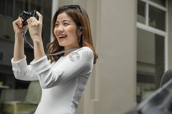 拿着相机拍照开心的青年女子图片