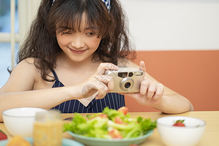 手拿相机拍美食的可爱女孩图片