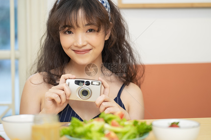 手拿相机拍美食的可爱女孩图片
