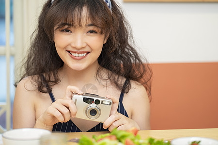 手拿相机拍美食的可爱女孩图片