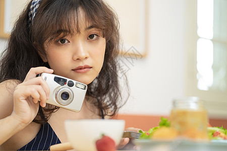 手拿相机拍美食的可爱女孩图片