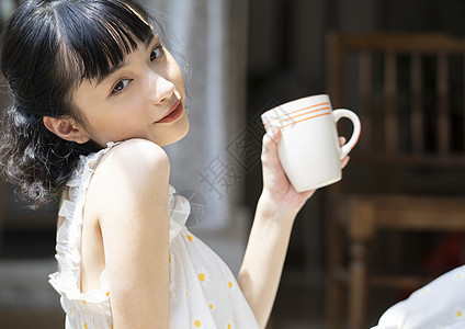 户外阳光下拿着水杯的年轻女子图片