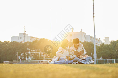 放松休息操场看书学习的大学生情侣背景