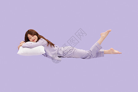 年轻少女趴在枕头上悬浮在空中睡觉图片