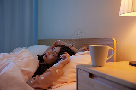 居家女性卧室睡觉和床头柜上的水杯美女高清图片素材