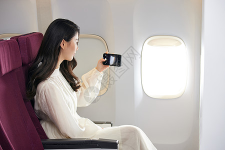 年轻美女在飞机上拍照图片