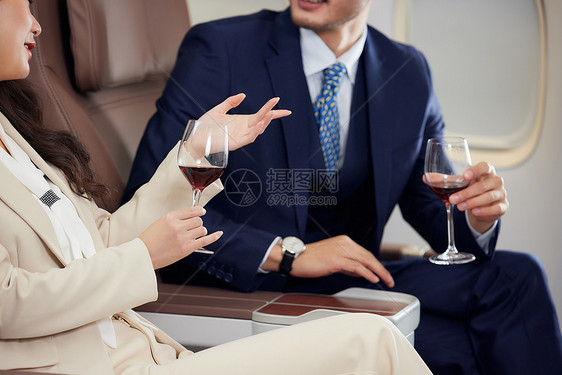商务男女飞机舱里喝酒聊天特写图片