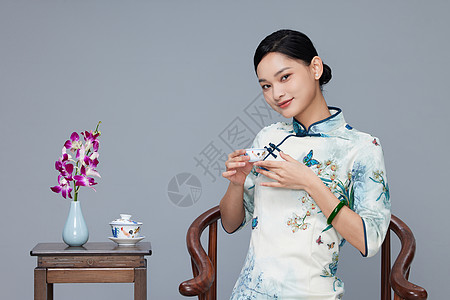 旗袍女性端坐喝茶背景图片