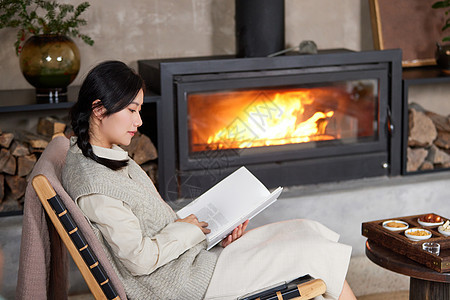 冬天坐在火炉边看书的女性图片