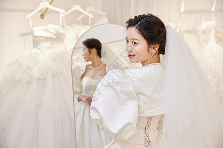 穿着婚纱站在试衣镜前的女性高清图片