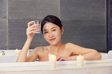 浴缸泡澡的美女手拿杯子喝水背景图片