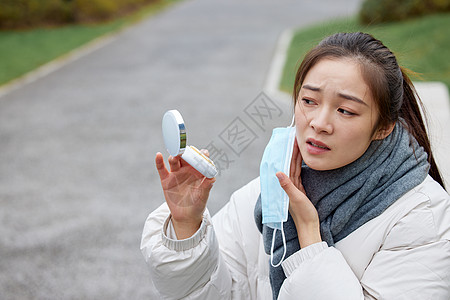 雾霾空气户外过敏的女性用化妆镜看脸背景