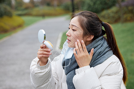 雾霾皮肤户外过敏的女性用化妆镜看脸背景