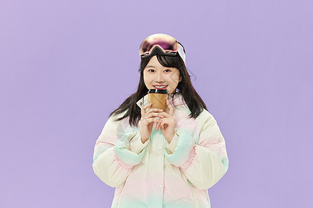戴着滑雪眼镜的女孩手握咖啡杯图片