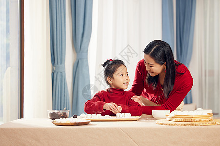 端着汤圆的妈妈元宵节妈妈陪着女儿包汤圆背景