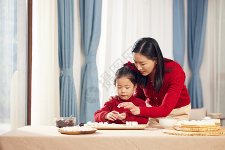 端着汤圆的妈妈元宵节妈妈陪着女儿包汤圆背景