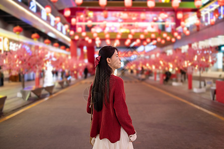 春节元素元旦春节街道上逛灯会的少女背影背景