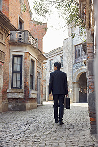 民国风建筑穿着中山装走在老旧街道上的男青年背景