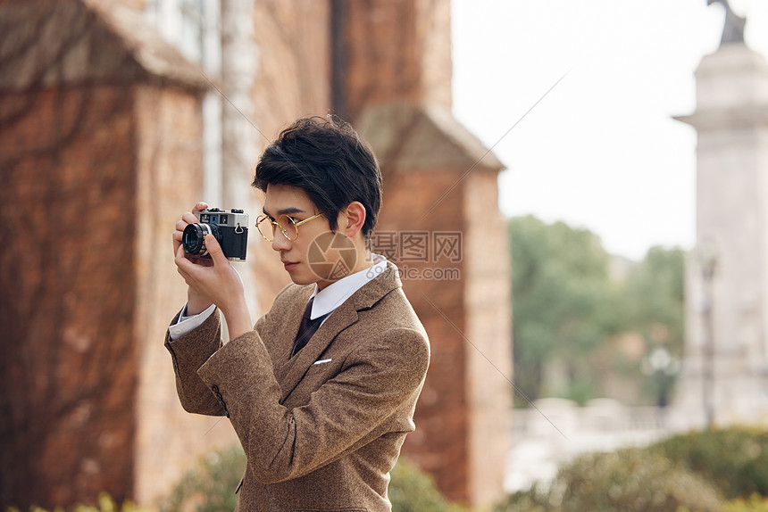 户外使用老式照相机拍照的男青年图片