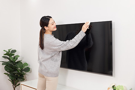 清洁电视机屏幕的居家女性背景图片