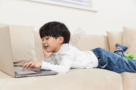 在沙发上玩耍看电脑的小朋友图片