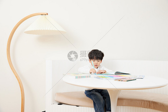 坐在桌前开心画画的可爱男孩图片