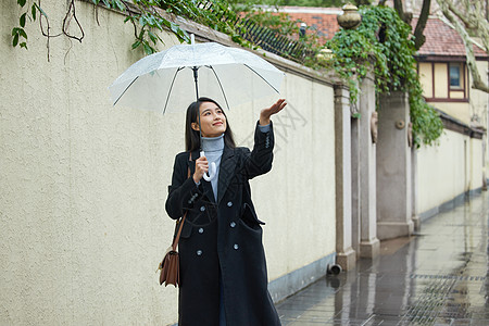 在雨中行走的女性用手接雨水背景图片