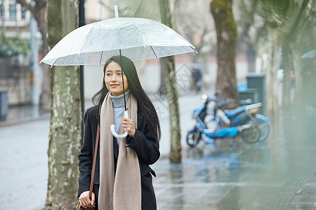 下雨天撑伞走在路边的女性图片