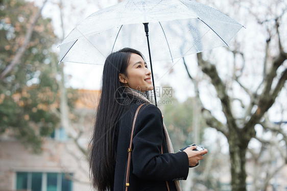 下雨天在城市里散步的女性图片