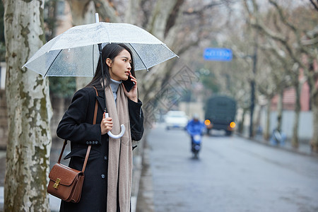 路边撑着雨伞着急打电话的女性图片